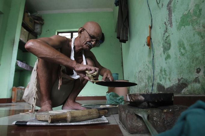 Mahesh Chaturvedi, 63, who dresses up like Mahatma Gandhi, cooks lunch at his residence in the outskirts of New Delhi October 23, 2012. Chaturvedi says that the soul of Gandhi resides in him and he has been sent to continue the work of Father of the Nation. After his self proclaimed transformation in 2002 as Gandhi, Chaturvedi has been travelling extensively and plays up to his startling resemblance to Gandhi at protests and demonstrations. Picture taken October 23, 2012. REUTERS/Mansi Thapliyal (INDIA - Tags: SOCIETY) Published: Lis. 26, 2012, 3:52 dop.