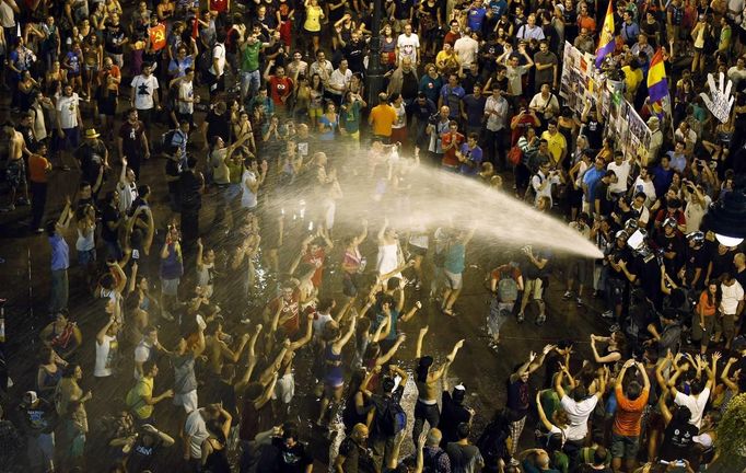 Firemen spray water over demonstrators during a protest against government austerity measures in Madrid July 19, 2012. A protest movement against the centre-right Spanish government's latest austerity measures swelled on Thursday as public sector workers stepped up demonstrations in Madrid and around the country after more than a week of spontaneous action. REUTERS/Sergio Perez (SPAIN - Tags: CIVIL UNREST BUSINESS POLITICS)