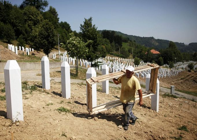 A worker carries a wooden frame while preparing graves for a ceremony at a memorial centre for Srebrenica Massacre victims in Potocari July 7, 2012. Tens of thousands of family members, foreign dignitaries and guests are expected to attend a ceremony in Srebrenica on July 11 marking the 17th anniversary of the massacre in which Bosnian Serb forces commanded by Ratko Mladic killed up to 8,000 Muslim men and boys. Nearly 510 identified victims will be buried at a memorial cemetery during the ceremony, their bodies found in some 60 mass graves around the town. REUTERS/Dado Ruvic (BOSNIA - Tags: POLITICS CONFLICT ANNIVERSARY) Published: Čec. 7, 2012, 3:30 odp.