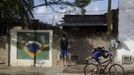 Gabriel Muniz, 11, gets ready to cycle to school as his brother Mateus looks on in Campos dos Goytacazes, 274 kilometres (170 miles) northeast of Rio de Janeiro August 23, 2012. Despite being born with malformation of his feet, fourth grader Gabriel puts in hours into soccer everyday in his neighbourhood. He aspires to be a professional soccer player just like his idol Argentina's Lionel Messi of Barcelona FC. REUTERS/Ricardo Moraes (BRAZIL - Tags: SPORT SOCCER SOCIETY HEALTH) Published: Srp. 24, 2012, 2:26 dop.