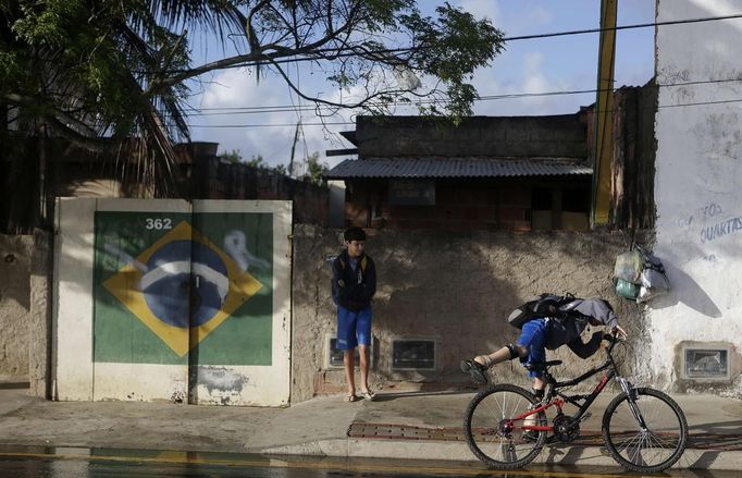 Gabriel Muniz, 11, gets ready to cycle to school as his brother Mateus looks on in Campos dos Goytacazes, 274 kilometres (170 miles) northeast of Rio de Janeiro August 23, 2012. Despite being born with malformation of his feet, fourth grader Gabriel puts in hours into soccer everyday in his neighbourhood. He aspires to be a professional soccer player just like his idol Argentina's Lionel Messi of Barcelona FC. REUTERS/Ricardo Moraes (BRAZIL - Tags: SPORT SOCCER SOCIETY HEALTH) Published: Srp. 24, 2012, 2:26 dop.