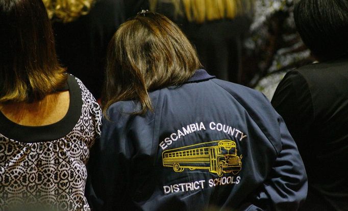 A woman wearing a bus driver's jacket from Escambia County, Florida attends the funeral for bus driver Charles Albert Poland Jr. at Ozark Civic Center, near Midland City, Alabama, February 3, 2013. Mourners in the small town of Midland City, Alabama, gathered on Sunday to bury a school bus driver slain during the abduction of a child taken captive and held for a sixth day by a gunman in an underground bunker. REUTERS/Phil Sears (UNITED STATES - Tags: CRIME OBITUARY) Published: Úno. 4, 2013, 1:18 dop.