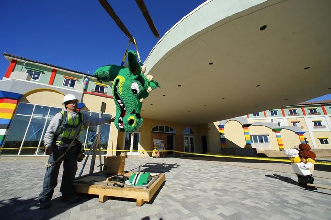 A worker helps lift a dragons head made of Lego into position as construction continues in North America's first ever Lego Hotel being built at Legoland in Carlsbad, California, January 17, 2013. The three-story, 250-room hotel will open on April 5. REUTERS/Mike Blake (UNITED STATES - Tags: SOCIETY TRAVEL) Published: Led. 17, 2013, 10:50 odp.