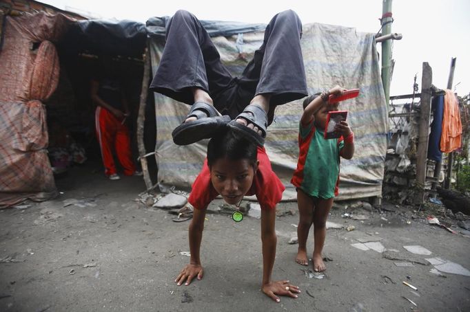 Drumpal Choudhary, 11, a street performer, does a hand stand in front of his hut in the slum on the bank of Manahara River before leaving to perform on the streets of Kathmandu August 15, 2012. Drumpal and his siblings, Shivani and Gchan, who came to Kathmandu from India 5 years ago, earn their living by performing tricks on the streets of Kathmandu. According to Drumpal, Shivani's older brother, they earn around $10 a day by performing tricks, which is not enough to feed their 10-member family living together in a small hut without a proper toilet or any basic needs. REUTERS/Navesh Chitrakar (NEPAL - Tags: SOCIETY IMMIGRATION POVERTY TPX IMAGES OF THE DAY) Published: Srp. 15, 2012, 4:03 odp.