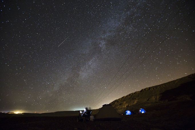 A meteor streaks across the sky in the early morning as people watching during the Perseid meteor shower in Ramon Carter near the town of Mitzpe Ramon, southern Israel