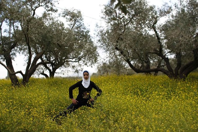 Palestinian runner Maslaha stretches as she practises at a field belonging to her family near Nablus