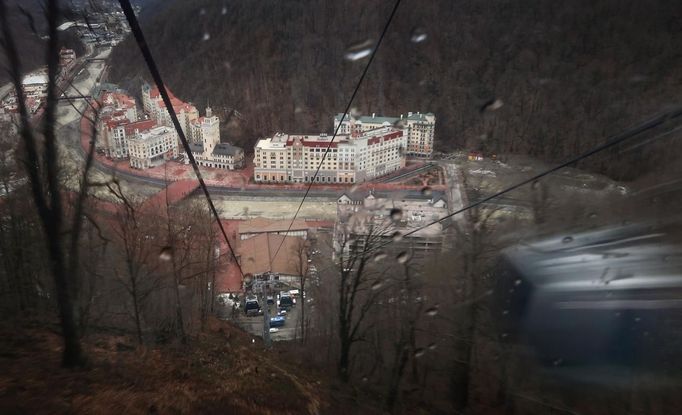 A picture taken through the tinted window of a moving gondola shows the winter sport resort of Rosa Khutor, a venue for the Sochi 2014 Winter Olympics near Sochi February 19, 2013. Although many complexes and venues in the Black Sea resort of Sochi mostly resemble building sites that are still under construction, there is nothing to suggest any concern over readiness. Construction will be completed by August 2013 according to organizers. The Sochi 2014 Winter Olympics opens on February 7, 2014. REUTERS/Kai Pfaffenbach (RUSSIA - Tags: BUSINESS CONSTRUCTION CITYSCAPE ENVIRONMENT SPORT OLYMPICS TPX IMAGES OF THE DAY) Published: Úno. 19, 2013, 12:38 odp.