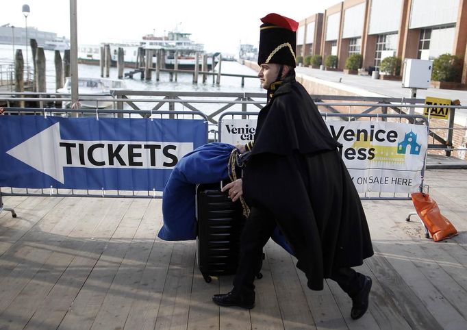 Marco Dilauro arrives to take a vaporetto, or waterbus, at Venice's Canal Grande, with a bag containing costumes which he made for the Venice Carnival January 25, 2013. Dilauro, 43, is a tax collector by day, but his real passion is making masks and costumes for the carnival. A resident of Como, northern Italy, he chooses fabrics, ribbons, lace and costume jewellery to make the period costumes after doing extensive research, and wears them at Carnival, which ends on the day before Ash Wednesday. Picture taken January 25, 2013. REUTERS/Alessandro Bianchi (ITALY - Tags: SOCIETY) Published: Led. 28, 2013, 12:13 dop.