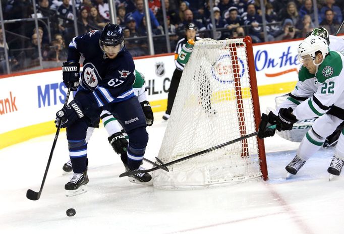 Mar 16, 2014; Winnipeg, Manitoba, CAN; Winnipeg Jets forward Michael Frolik (67) controls the puck behind the Dallas net as Dallas Stars forward Colton Sceviour (22) chal