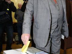 Karel Schwarzenberg při volbě: do urny dává žlutý hlasovací lístek, správnou obálku drží v druhé ruce.