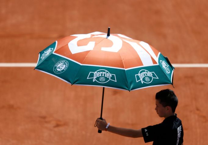 A court boy holds an umbrella during the women's singles match betwween Simona Halep of Romania and Evgeniya Rodina of Russia at the French Open tennis tournament at the