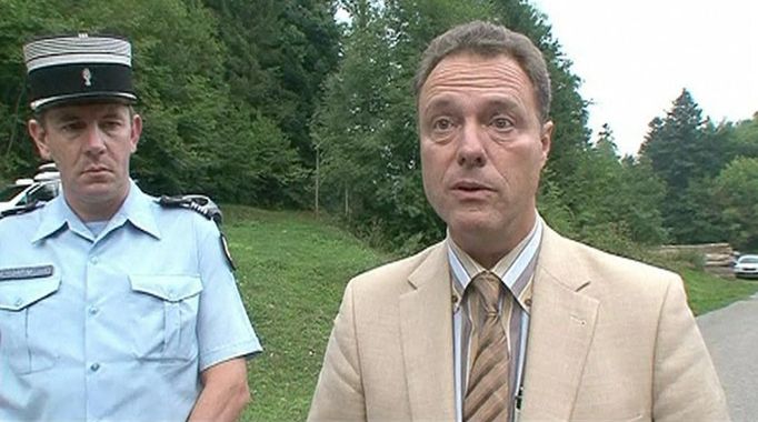 Annecy public prosecutor Eric Maillaud speaks to the media on a road near Annecy Lake in Chevaline, southeastern France, in this still image taken from video September 5, 2012. French police found four people shot dead near a lake in southeastern France on Wednesday, three of them in a British-registered BMW car, Maillaud said. A fourth body, apparently a person who had been riding a bicycle, was found nearby. A badly injured eight-year-old girl, also found nearby, was taken to hospital by helicopter, he said. MANDATORY CREDIT REUTERS/M6 via Reuters TV (FRANCE - Tags: CRIME LAW) FOR EDITORIAL USE ONLY. NOT FOR SALE FOR MARKETING OR ADVERTISING CAMPAIGNS. THIS IMAGE HAS BEEN SUPPLIED BY A THIRD PARTY. IT IS DISTRIBUTED, EXACTLY AS RECEIVED BY REUTERS, AS A SERVICE TO CLIENTS. MANDATORY CREDIT. FRANCE OUT. NO COMMERCIAL OR EDITORIAL SALES IN FRANCE Published: Zář. 5, 2012, 8:23 odp.