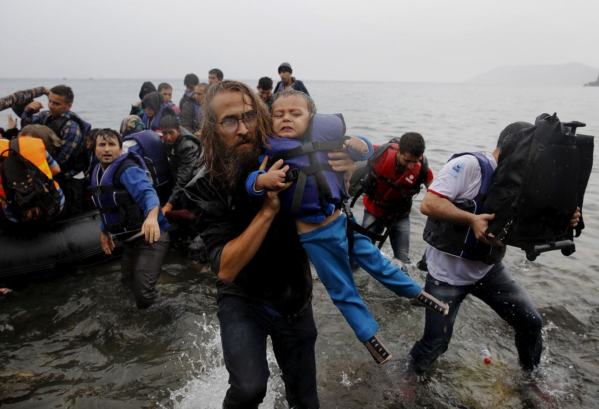 Dobrovolník pomáhá z lodi syrskému dítěti.