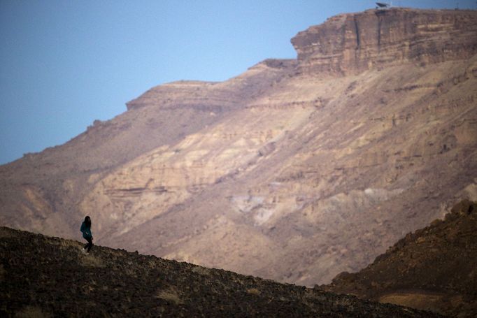 A woman walks on a hill before sunrise after the Perseid meteor shower, in Ramon Carter near the town of Mitzpe Ramon, southern Israel