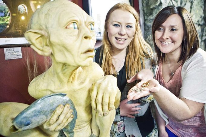 Visitors pose next to a sculpture of the J. R. R. Tolkien character Gollum at the Weta Cave museum in Wellington in this September 25, 2012 handout photograph. New Zealand's capital city was rushing to complete its transformation into a haven for hairy feet and pointed ears on November 27, 2012 as stars jetted in for the long-awaited world premiere of the first movie of the Hobbit trilogy. Picture taken September 25, 2012. REUTERS/Positively Wellington Tourism/Handout (NEW ZEALAND - Tags: ENTERTAINMENT SOCIETY) NO SALES. NO ARCHIVES. FOR EDITORIAL USE ONLY. NOT FOR SALE FOR MARKETING OR ADVERTISING CAMPAIGNS. THIS IMAGE HAS BEEN SUPPLIED BY A THIRD PARTY. IT IS DISTRIBUTED, EXACTLY AS RECEIVED BY REUTERS, AS A SERVICE TO CLIENTS Published: Lis. 27, 2012, 1:35 dop.