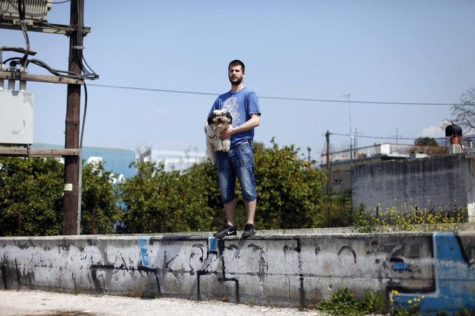 Thanos Kehagias holds his mother's dog Vagos as he poses for a picture outside his student flat in the Greek city of Patra