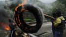 A coal miner uses a plank to carry a burning tire to be used as a barricade in front of the main gate of the "Pozo Santiago" mine in Caborana, near Oviedo, northern Spain June 18, 2012. Spanish coal mining unions are taking part in a general strike in northern Spain mining areas to protest against government action to cut coal subsidies. REUTERS/Eloy Alonso (SPAIN - Tags: CIVIL UNREST BUSINESS EMPLOYMENT ENERGY) Published: Čer. 18, 2012, 1:09 odp.