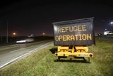 Cedule s nápisem "Operace uprchlíci" informovala auta mířící na terminál, kam vojenské letadlo se syrskými pasažéry přistálo.