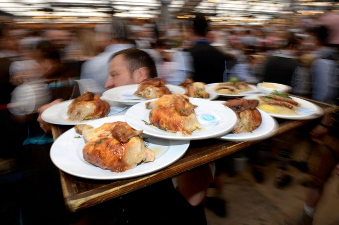 Číšník roznášející pečená kuřata na Oktoberfestu v Mnichově.