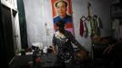 A woman stands near a poster of former Chinese leader Mao Zedong at her gas station office near Badong, 100km (62 miles) from the Three Gorges dam in Hubei province in this August 6, 2012 file photo. China relocated 1.3 million people during the 17 years it took to complete the Three Gorges dam. Even after finishing the $59 billion project last month, the threat of landslides along the dam's banks will force tens of thousands to move again. It's a reminder of the social and environmental challenges that have dogged the world's largest hydroelectric project. While there has been little protest among residents who will be relocated a second time, the environmental fallout over other big investments in China has become a hot-button issue ahead of a leadership transition this year. Picture taken on August 6, 2012. To match story CHINA-THREEGORGES/ REUTERS/Carlos Barria/Files (CHINA - Tags: POLITICS ENVIRONMENT BUSINESS ENERGY) Published: Srp. 22, 2012, 8:47 odp.