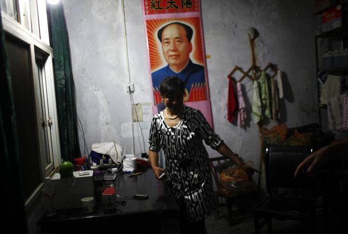 A woman stands near a poster of former Chinese leader Mao Zedong at her gas station office near Badong, 100km (62 miles) from the Three Gorges dam in Hubei province in this August 6, 2012 file photo. China relocated 1.3 million people during the 17 years it took to complete the Three Gorges dam. Even after finishing the $59 billion project last month, the threat of landslides along the dam's banks will force tens of thousands to move again. It's a reminder of the social and environmental challenges that have dogged the world's largest hydroelectric project. While there has been little protest among residents who will be relocated a second time, the environmental fallout over other big investments in China has become a hot-button issue ahead of a leadership transition this year. Picture taken on August 6, 2012. To match story CHINA-THREEGORGES/ REUTERS/Carlos Barria/Files (CHINA - Tags: POLITICS ENVIRONMENT BUSINESS ENERGY) Published: Srp. 22, 2012, 8:47 odp.