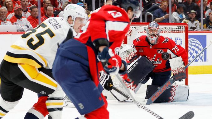 Brankář Capitals Charlie Lindgren sleduje Jakuba Vránu v souboji.