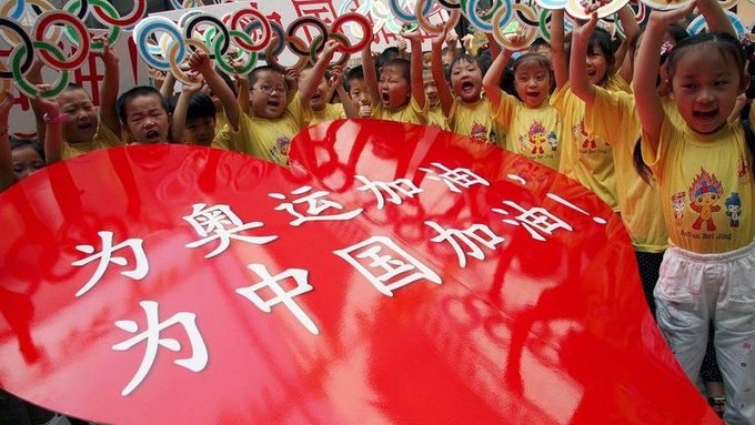 Čínské děti se radují z blížící se olympiády. Nápis na červeném srdci říká: "Povzbudíme olympioniky, povzbudíme Čínu!"