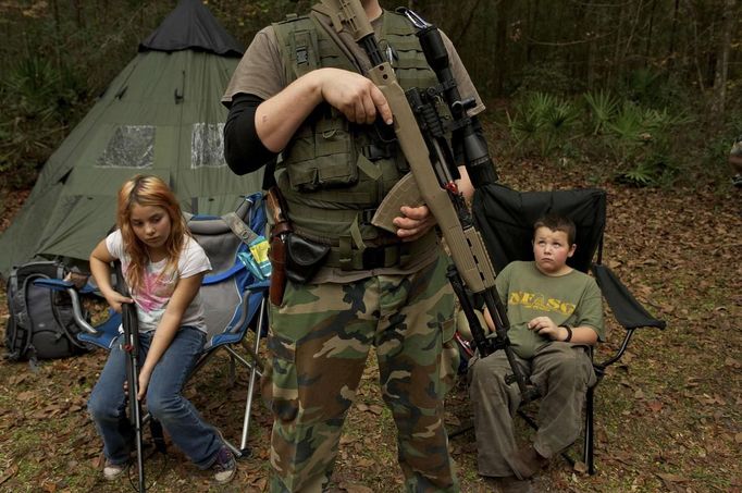 Members of the North Florida Survival Group wait with their rifles before heading out to perform enemy contact drills during a field training exercise in Old Town, Florida, December 8, 2012. The group trains children and adults alike to handle weapons and survive in the wild. The group passionately supports the right of U.S. citizens to bear arms and its website states that it aims to teach "patriots to survive in order to protect and defend our Constitution against all enemy threats". Picture taken December 8, 2013. REUTERS/Brian Blanco (UNITED STATES - Tags: SOCIETY POLITICS TPX IMAGES OF THE DAY) ATTENTION EDITORS: PICTURE 19 OF 20 FOR PACKAGE 'TRAINING CHILD SURVIVALISTS' SEARCH 'FLORIDA SURVIVAL' FOR ALL IMAGES Published: Úno. 22, 2013, 1:01 odp.