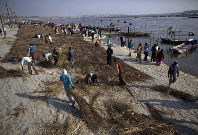 Workers spread dry grass on the banks of the river Ganges ahead of the "Kumbh Mela" (Pitcher Festival) in the northern Indian city of Allahabad January 11, 2013. During the festival, Hindus take part in a religious gathering on the banks of the river Ganges. "Kumbh Mela" will return to Allahabad in 12 years. REUTERS/Ahmad Masood (INDIA - Tags: RELIGION SOCIETY) Published: Led. 11, 2013, 6:32 odp.