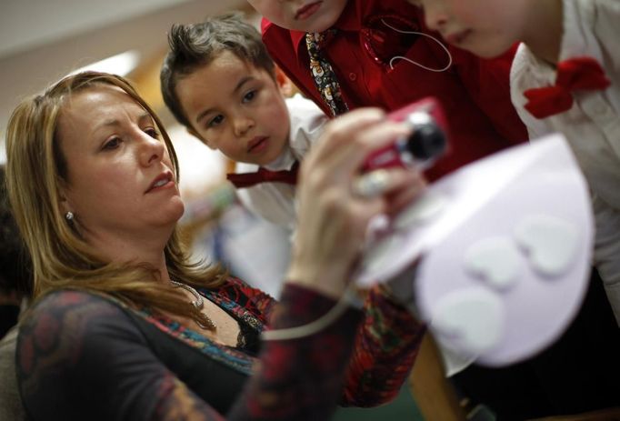 Theresa Volpe shows her son Jaidon Santos-Volpe pictures she took at the Valentine's Day Ball at Baker Demonstration School in Wilmette, Illinois, February 13, 2013. Volpe and her partner Mercedes Santos are a same-sex couple raising two of their biological children as they struggle to get same-sex marriages passed into law in Illinois. Picture taken February 13, 2013. REUTERS/Jim Young (UNITED STATES - Tags: SOCIETY) Published: Bře. 25, 2013, 6:08 odp.