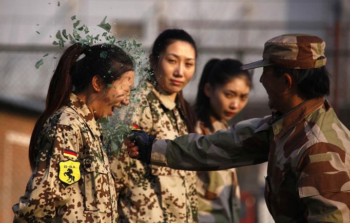 RNPS IMAGES OF THE YEAR 2012 - An instructor from the Tianjiao Special Guard/Security Consultant Ltd. Co, smashes a bottle over a female recruit's head during a training session for China's first female bodyguards in Beijing January 13, 2012. According to the company, the training session consists of 20 women, mostly college graduates, who will undergo 8-10 months of training to develop sufficient skills to become security guards. The company will then offer the best trainee a chance to attend the International Security Academy in Israel. REUTERS/David Gray (CHINA - Tags: SOCIETY TPX IMAGES OF THE DAY) Published: Pro. 3, 2012, 1:02 dop.