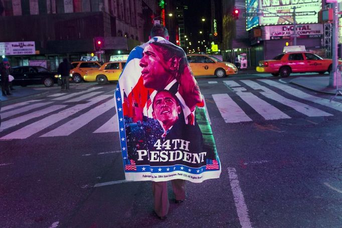 Muž s plakátem na zádech oslavuje výhru Baracka Obamy na Times Square v New Yorku.