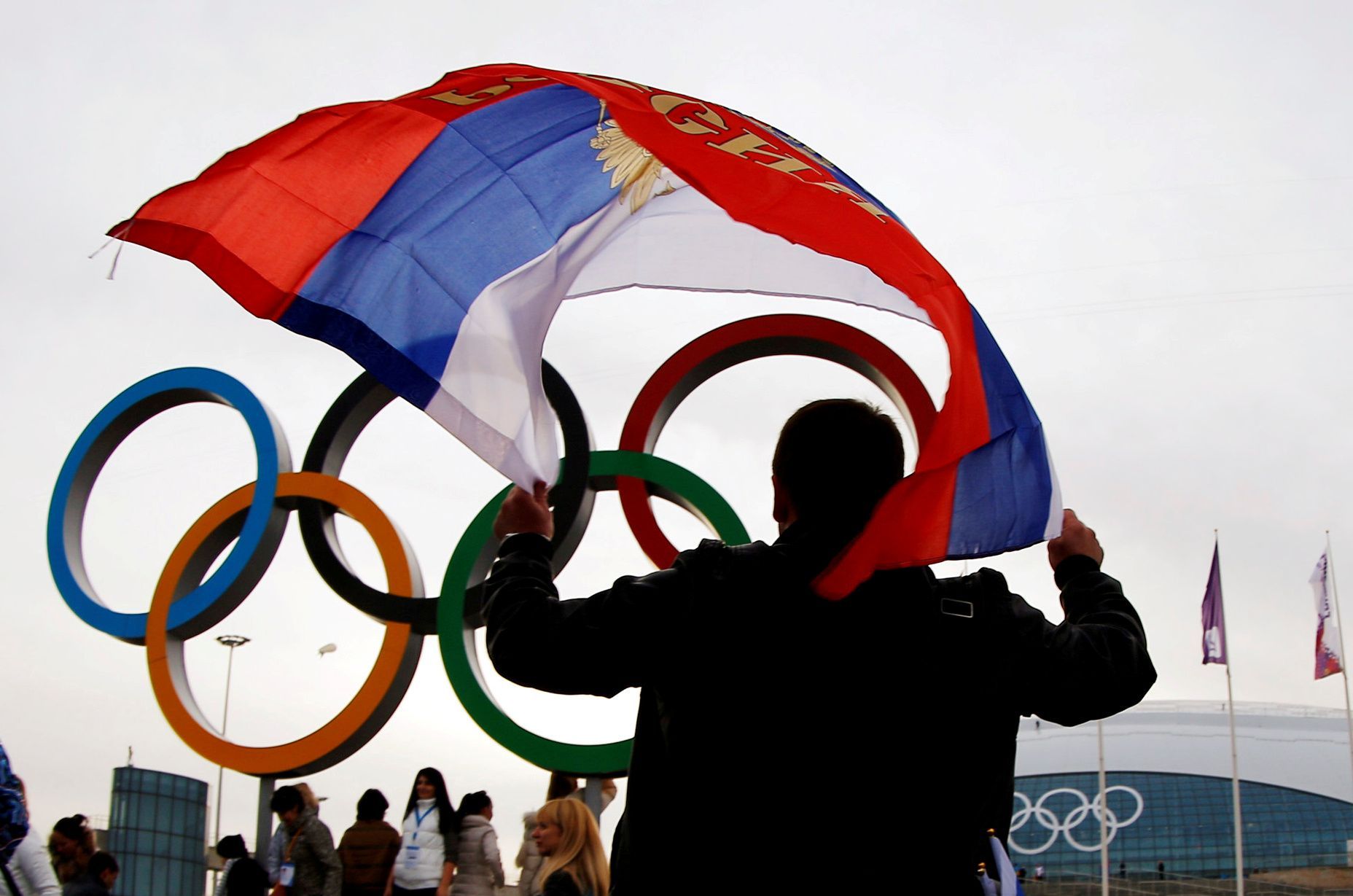 FILE PHOTO: Man carries the Russian flag past the Olympic rings at the Olympic Park during the 2014 Sochi Winter Olympics