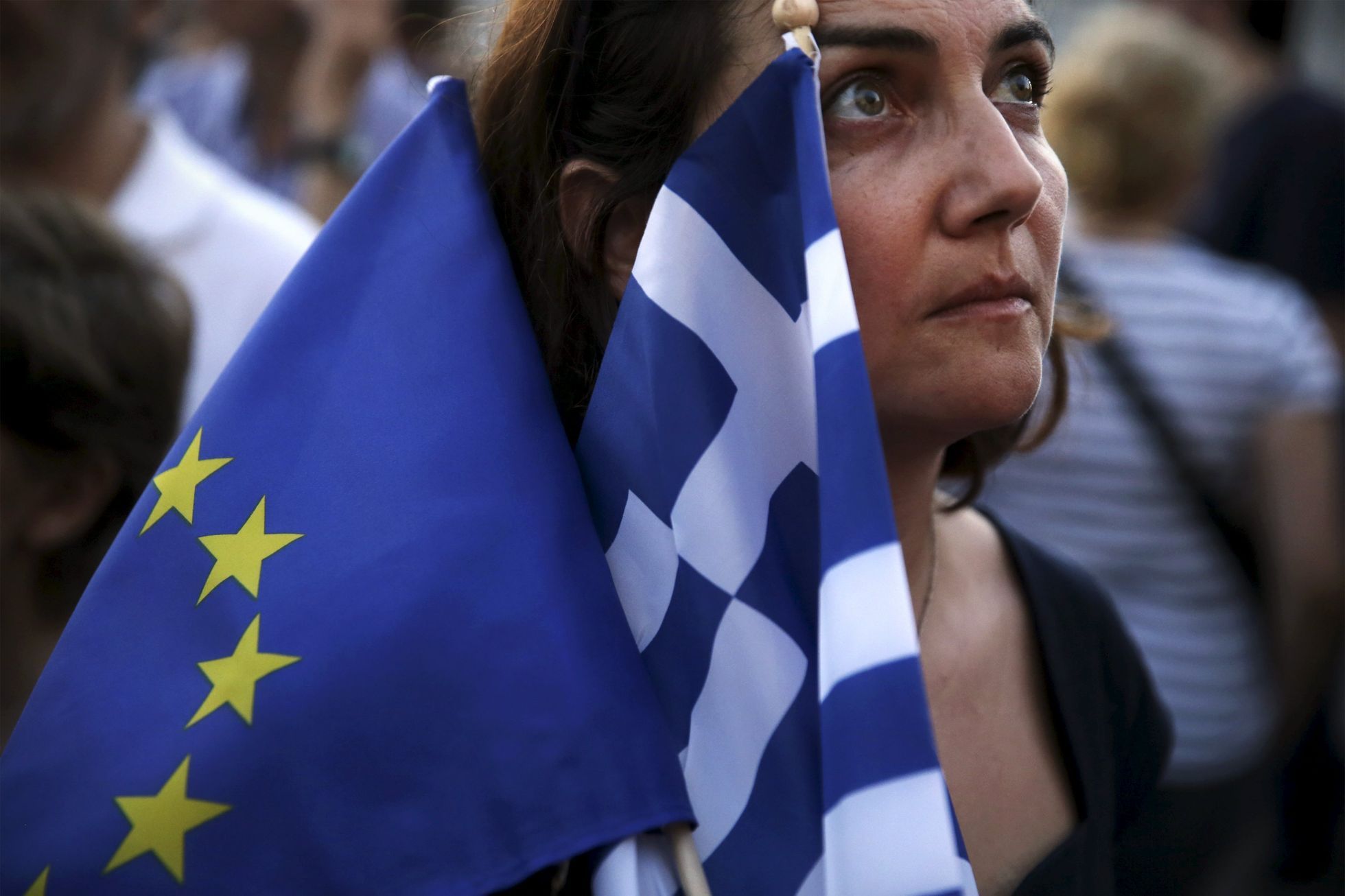 Řecko A pro-Euro protester holds a European Union and a Greek national flag during a rally in front of the parliament building in Athens