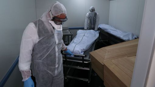 Pracovníci márnice v Bruselu přenášejí tělo jedné z obětí koronaviru.