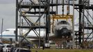 Space center workers walk past the space shuttle Discovery after it was attached to a lifting harness in the Mate Demate facility at Kennedy Space Center in Cape Canaveral