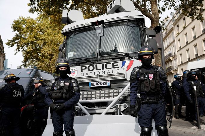 Francouzská pořádková policie stojí v pozici před vozidlem s vodním dělem během demonstrace v Paříži v rámci celonárodní stávky.