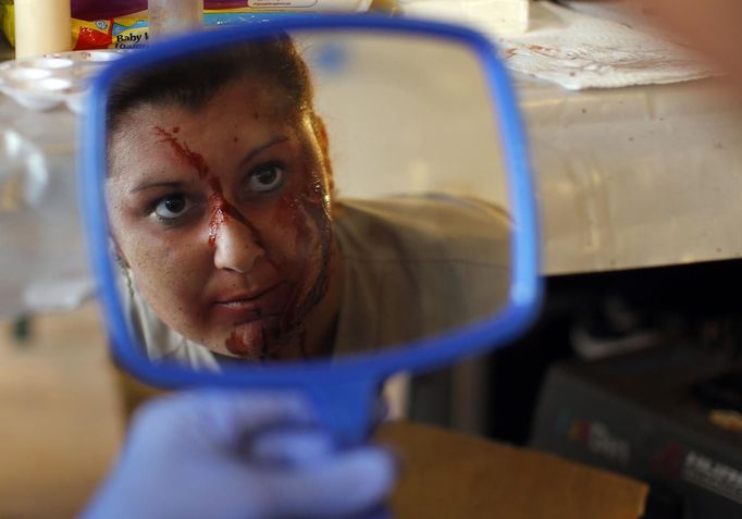 A zombie checks her make-up in a mirror before chasing runners on the "Run for Your Lives" 5K obstacle course race in Amesbury, Massachusetts May 5, 2012. Runners face man-made and natural obstacles on the course, while being chased by zombies, who try to take "health" flags off the runners belts. REUTERS/Brian Snyder (UNITED STATES - Tags: SPORT SOCIETY) Published: Kvě. 5, 2012, 8:15 odp.