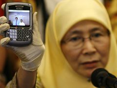 Manželka Anwara Ibrahima Wan Azíza Wan Ismailová ukazuje novinářům fotografii, na níž je zachycen mladík, který obvinil jejího manžela, v kanceláři vicepremiéra. Jde o jasný důkaz spiknutí, říká