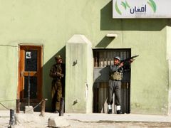 Afghánští policisté se kryjí během přestřelky u budovy ministerstva spravedlnosti, kterou napadli bojovníci Talibanu