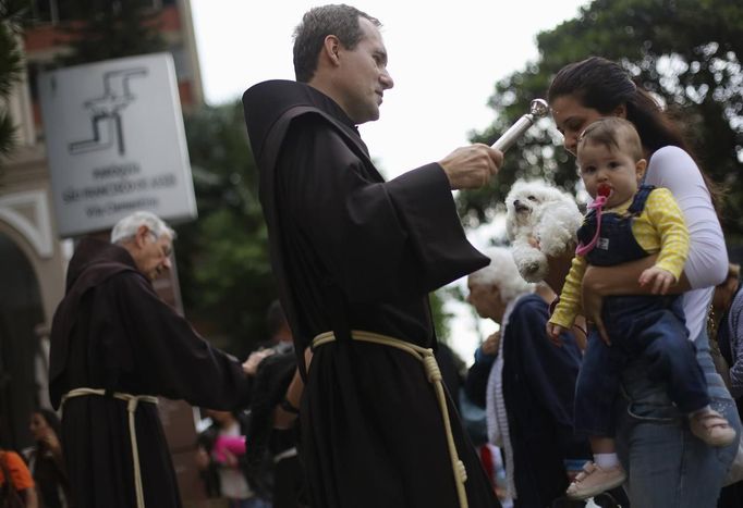 Žena dří v náručí batole a psíka. Svěcená voda od kněze tentokrát směřuje na psa. Kostel Sao Francisco de Assis v Sao Paulu se totiž pochopitelně přidal ke mši za tohoto světce.