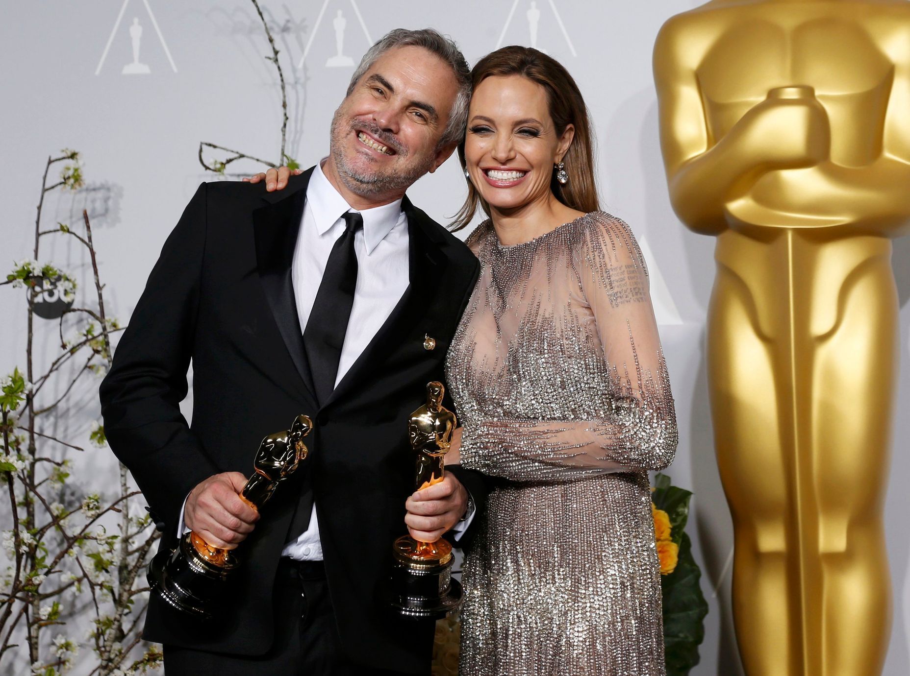 Cuaron poses with the Oscars for best director and for best film editing for &quot;Gravity&quot; with presenter Jolie backstage at the 86th Academy Awards in Hollywood