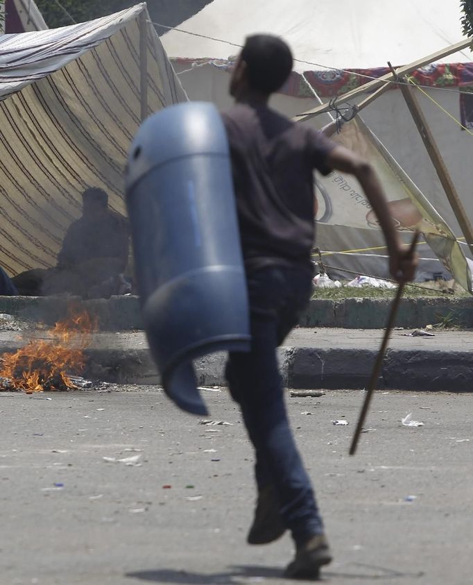 A supporter of Egypt's President Mohamed Mursi runs with a stick and shield after night clashes with anti-Mursi around Cairo University and Nahdet Misr Square in Giza, on the outskirts of Cairo July 3, 2013. The general command of the Egyptian armed forces is currently holding a crisis meeting, a military source told Reuters on Wednesday. At least 16 people were killed on Wednesday and 200 wounded when gunmen opened fire on supporters of Mursi who were rallying outside Cairo University, state television quoted a Health Ministry spokesman as saying. REUTERS/Amr Abdallah Dalsh (EGYPT - Tags: POLITICS CIVIL UNREST) Published: Čec. 3, 2013, 12:08 odp.