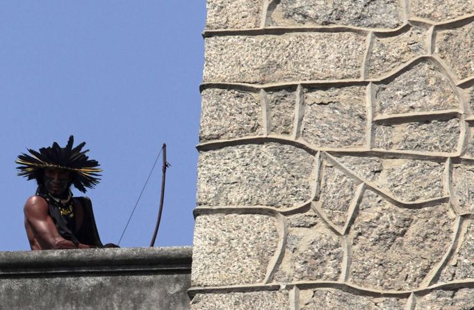 A Native Indian holds a bow and arrow as he watches police from the roof of the Brazilian Indian Museum in Rio de Janeiro March 22, 2013. Brazilian military police took position early morning outside the Indian museum, where a native Indian community of around 30 individuals who have been living in the abandoned Indian Museum since 2006. Indians were summoned to leave the museum in 72 hours by court officials since last week, local media reported. The group is fighting against the destruction of the museum, which is next to the Maracana Stadium. REUTERS/Sergio Moraes (BRAZIL - Tags: POLITICS MILITARY CIVIL UNREST) Published: Bře. 22, 2013, 1:26 odp.