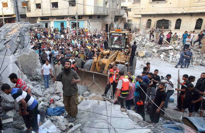 Palestinci troskách zničených domů hledají těla obětí po izraelském raketovém náletu v Rafah v jižní části Pásma Gazy.