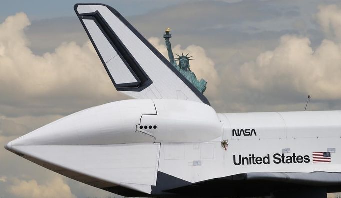 The Space Shuttle Enterprise, passes the Statue of Liberty as it rides on a barge in New York harbor, June 6, 2012. The Space Shuttle Enterprise was being moved up the Hudson River to be placed at the Intrepid Sea, Air and Space Museum. REUTERS/Mike Segar (UNITED STATES - Tags: TRANSPORT SCIENCE TECHNOLOGY) Published: Čer. 6, 2012, 6:10 odp.