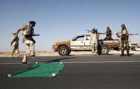 Libye - povstalec dupající po vlajce Kaddáfího