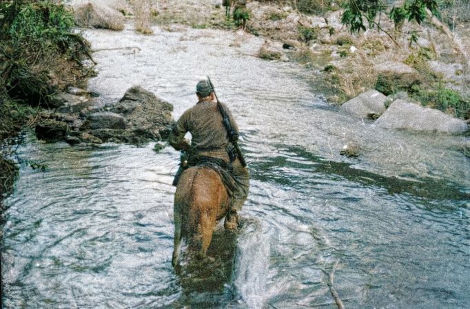 Zřídkakdy Castro přijal  jízdu na mule, kromě této příležitosti, kdy se s horečkou musel dostat k lékaři. Sierra Maestra, Kuba, Cca 1957 - 1958. Kolorováno