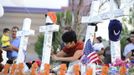 Annette Lucero writes on a cross with a marker at the memorial site for the people killed by a gunman last Friday in the Century 16 movie theater in Aurora, Colorado, July 22, 2012. Residents of a Denver suburb mourned their dead on Sunday from a shooting rampage by a gunman who killed 12 people and wounded 58 after opening fire at a cinema showing the new Batman movie. REUTERS/Jeremy Papasso (UNITED STATES - Tags: CRIME LAW CIVIL UNREST OBITUARY) Published: Čec. 23, 2012, 3:53 dop.