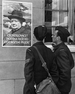 Válečný zpravodaj a spisovatel Jiří Mucha, spolu s přítelem před jedním z plakátů vylepených v ulicích válečného Londýna. Autorem fotografie je Erich Auerbach.